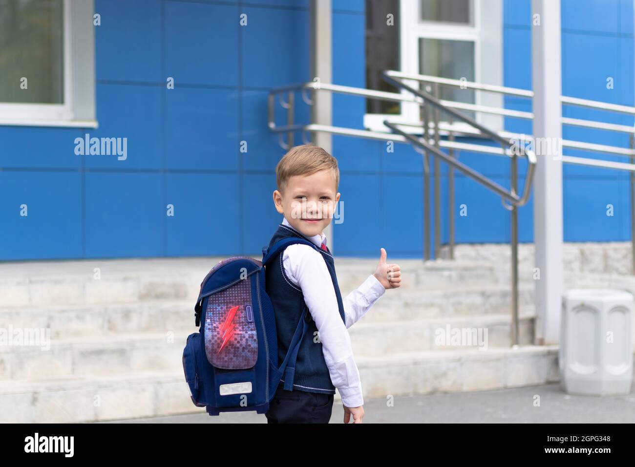 A cute first grader boy in a school uniform with a schoolbag goes to school on a sunny autumn day. Celebration on September 1st. Knowledge day. Select Stock Photo