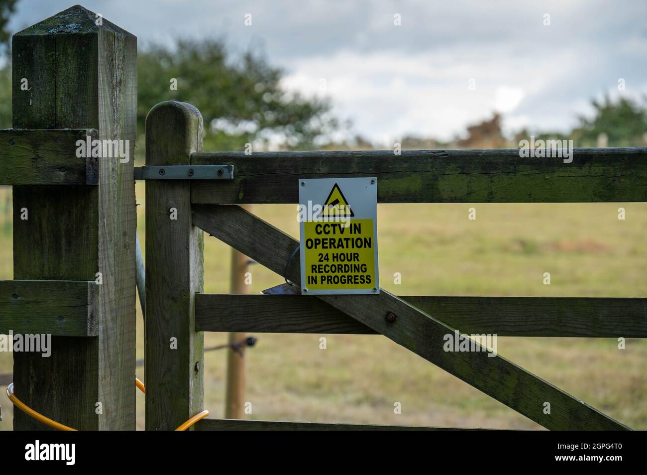 A warning sign on a farmers gate indicating 24hour CCTV in use Stock Photo