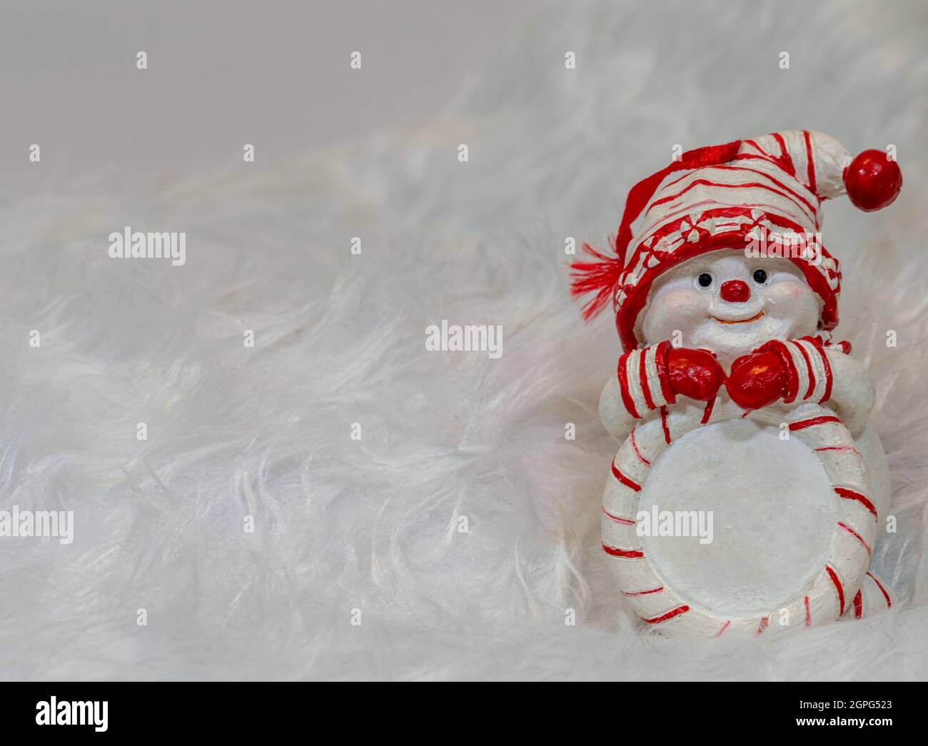 White Christmas background with a snowman wearing a red and white hat and a scarf. Stock Photo