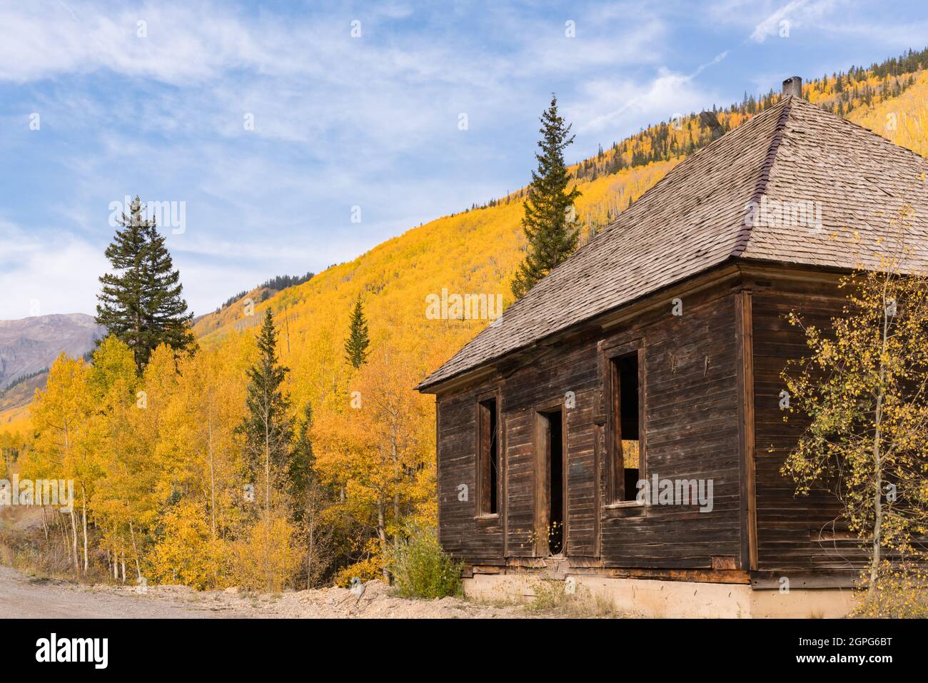 Old abandoned mining building with the yellow aspen trees in the Sun Juan Mountains of Colorado Stock Photo