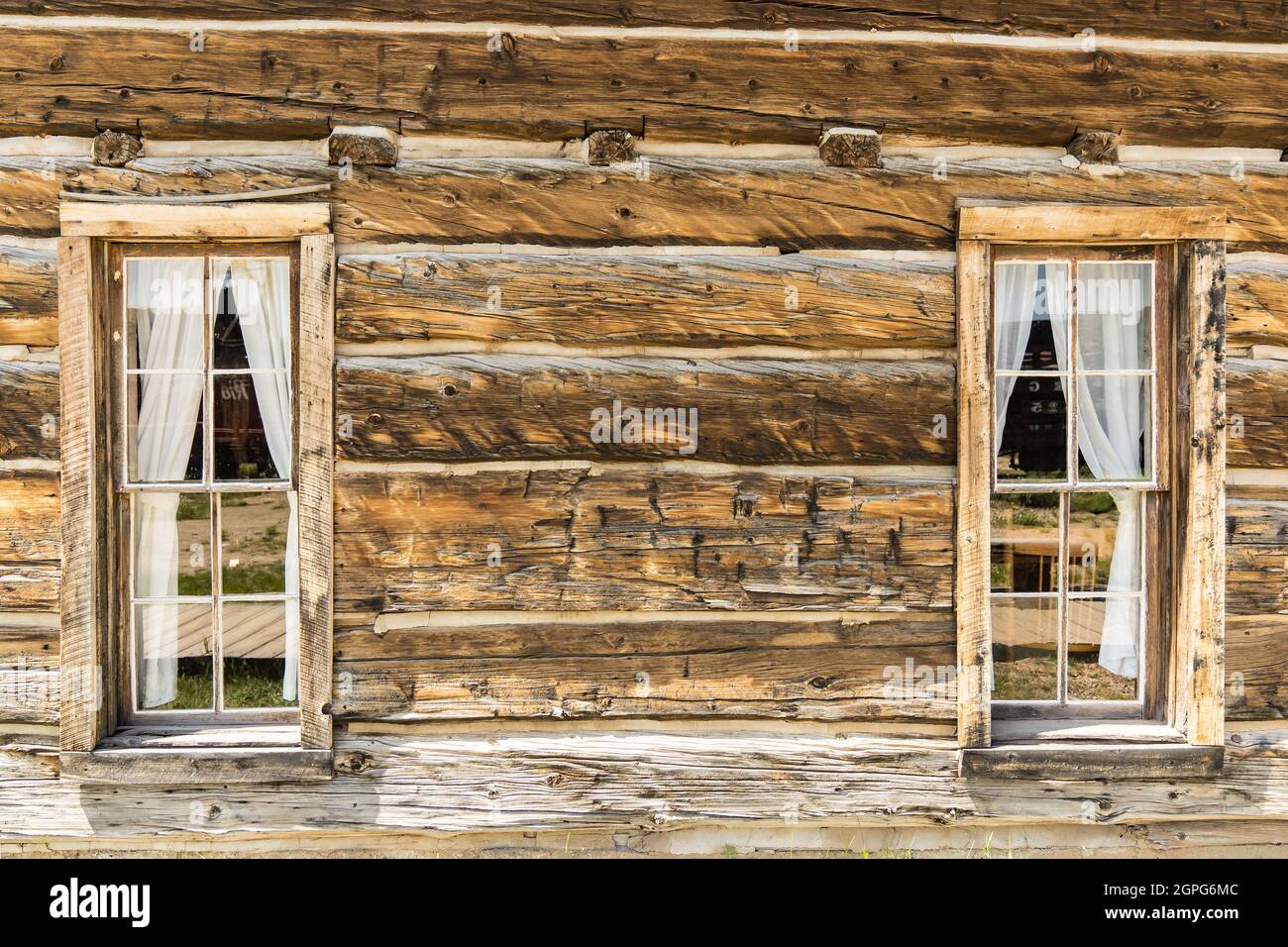 Old weathered wood windows with a curtain in rustic log cabin Stock Photo