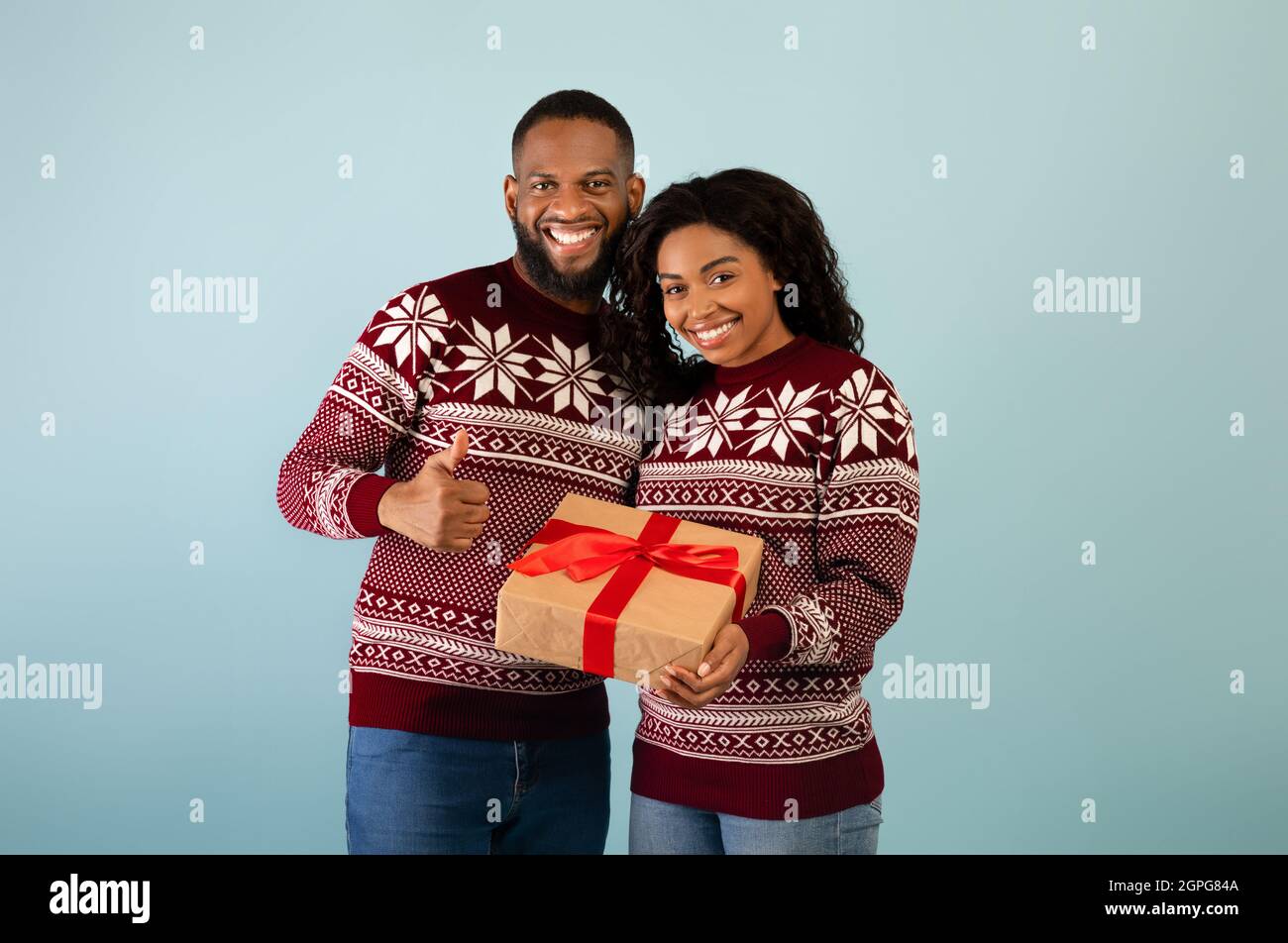 Romantic african american couple in Christmas outfits holding gift box ...