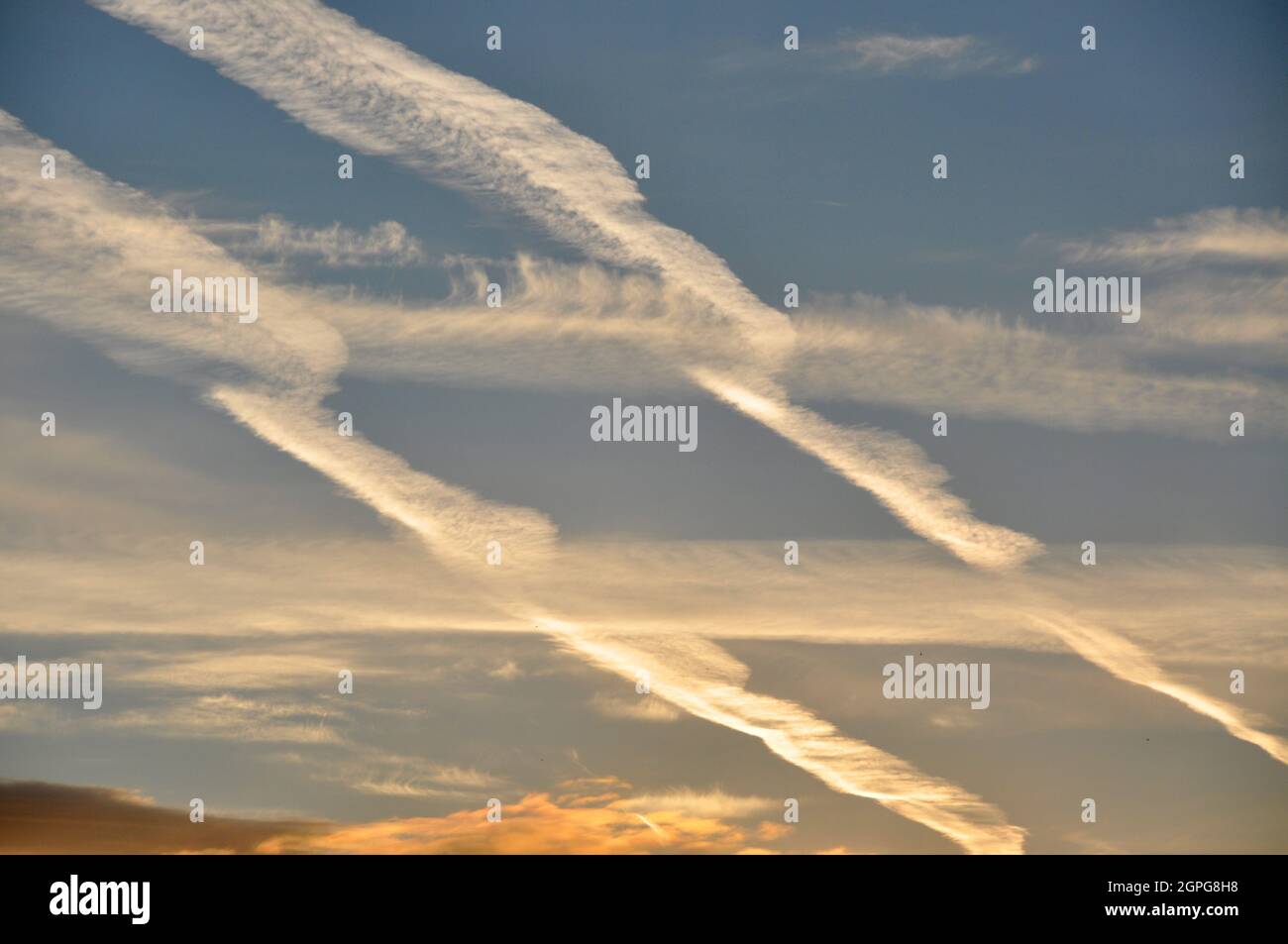 Contrails in a blue sky, caused by aircraft jet engine emissions in the busy skies above Manchester, England Stock Photo