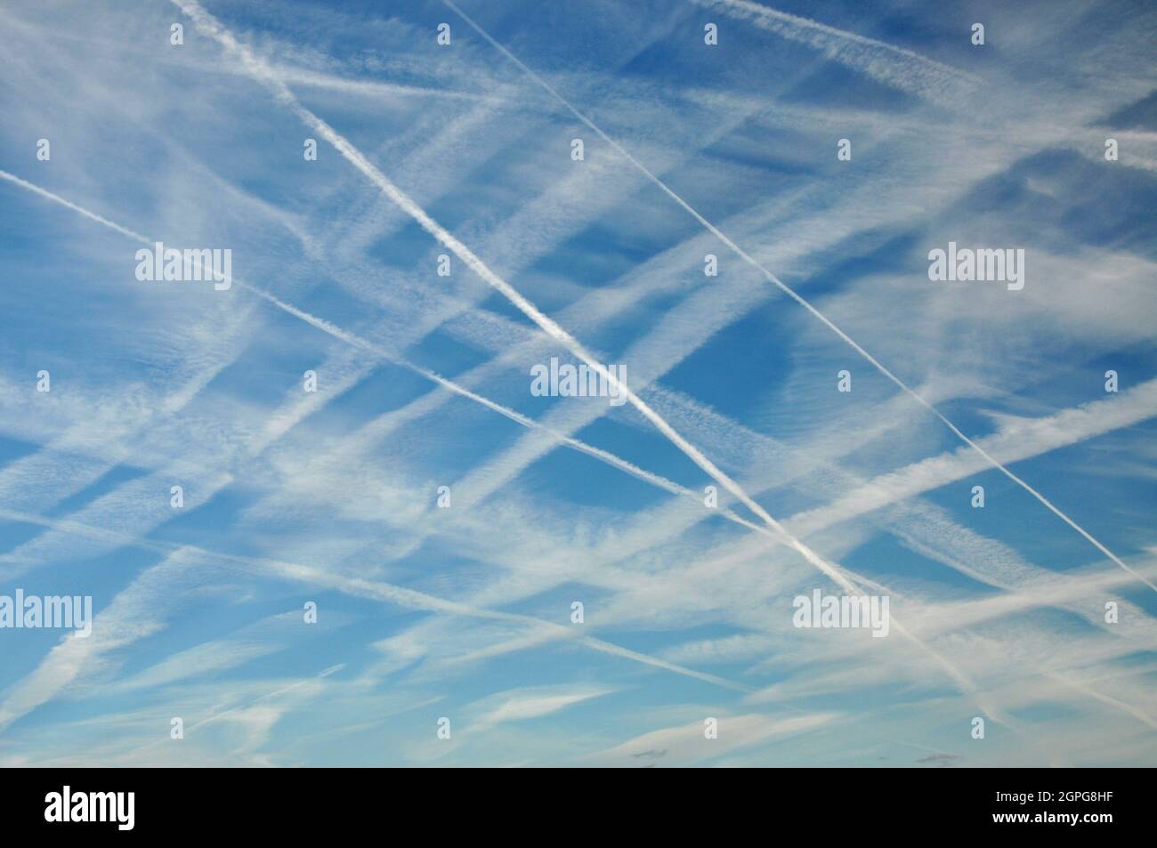 Contrails in a blue sky, caused by aircraft jet engine emissions in the busy skies above Manchester, England Stock Photo