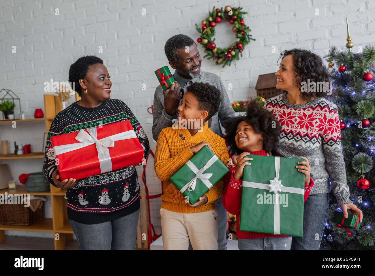 pleased african american family with christmas presents looking at each other at home Stock Photo