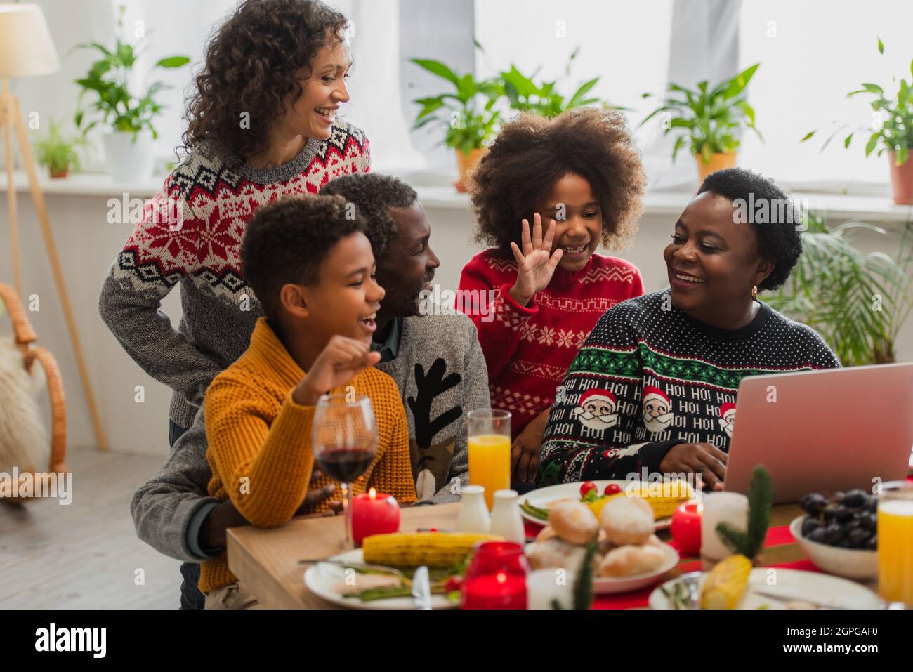 cheerful african american girl waving hand during video call near ...