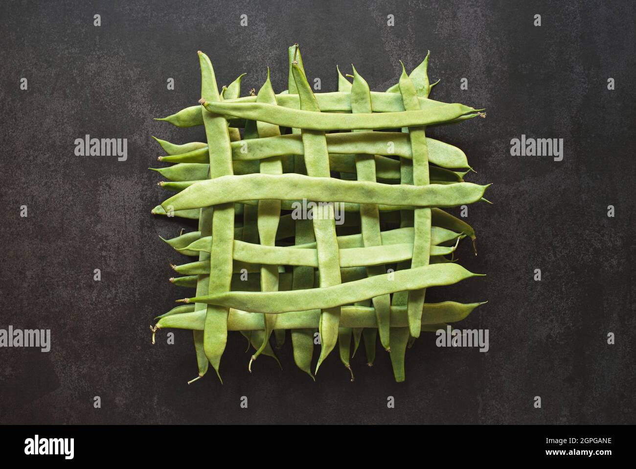 Top view of whole green beans in a geometric pattern on dark background Stock Photo