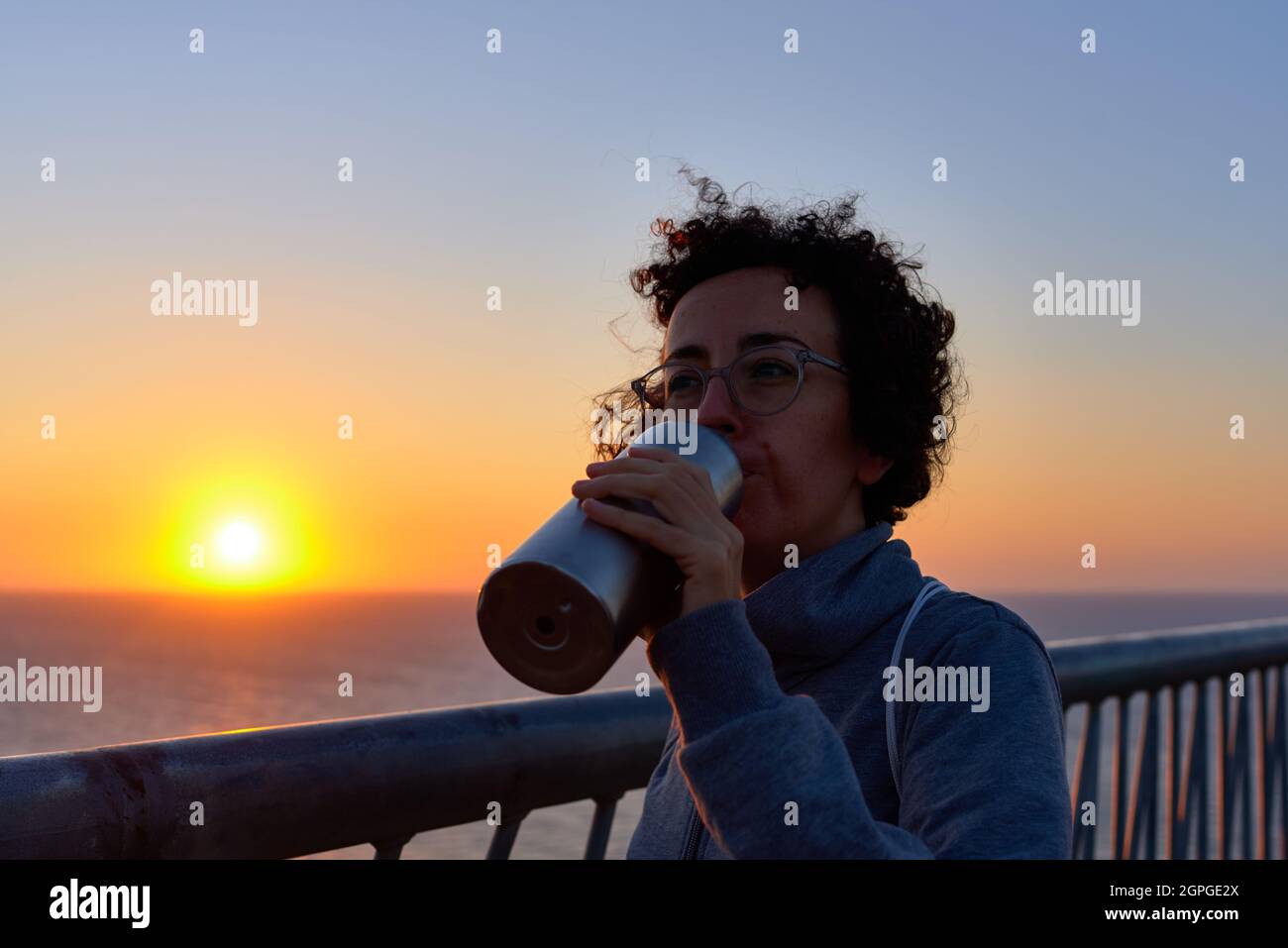 A woman drinking water during a sunrise Stock Photo Alamy