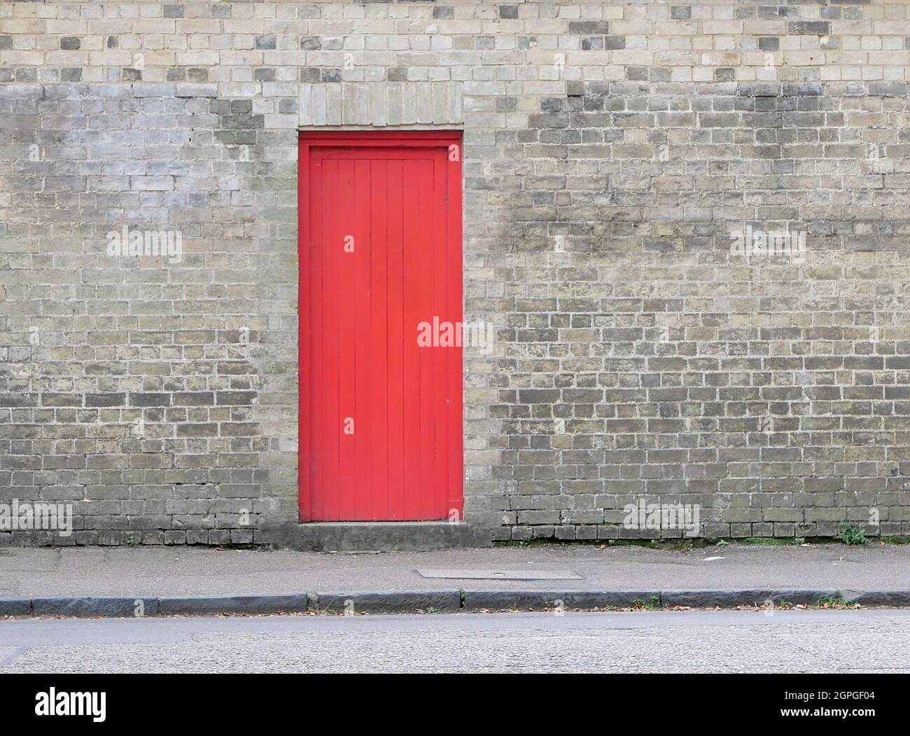 Bright red door embedded in grey brick wall with copy space Stock Photo