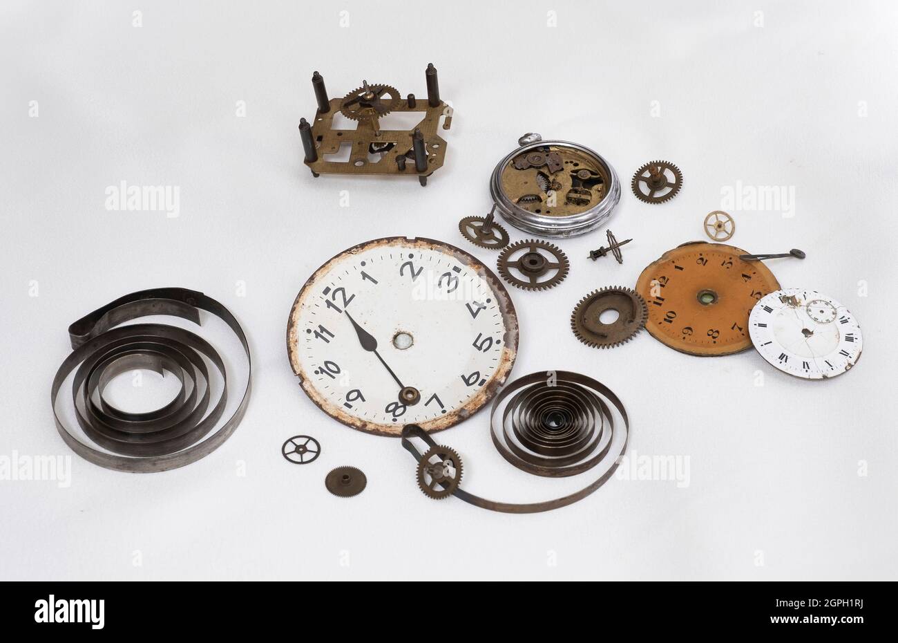 disassembled parts of an antique clock, clock hands, gear wheels, torsion springs, clock faces, scrapped antique clock parts, sprocket , dials, piano Stock Photo