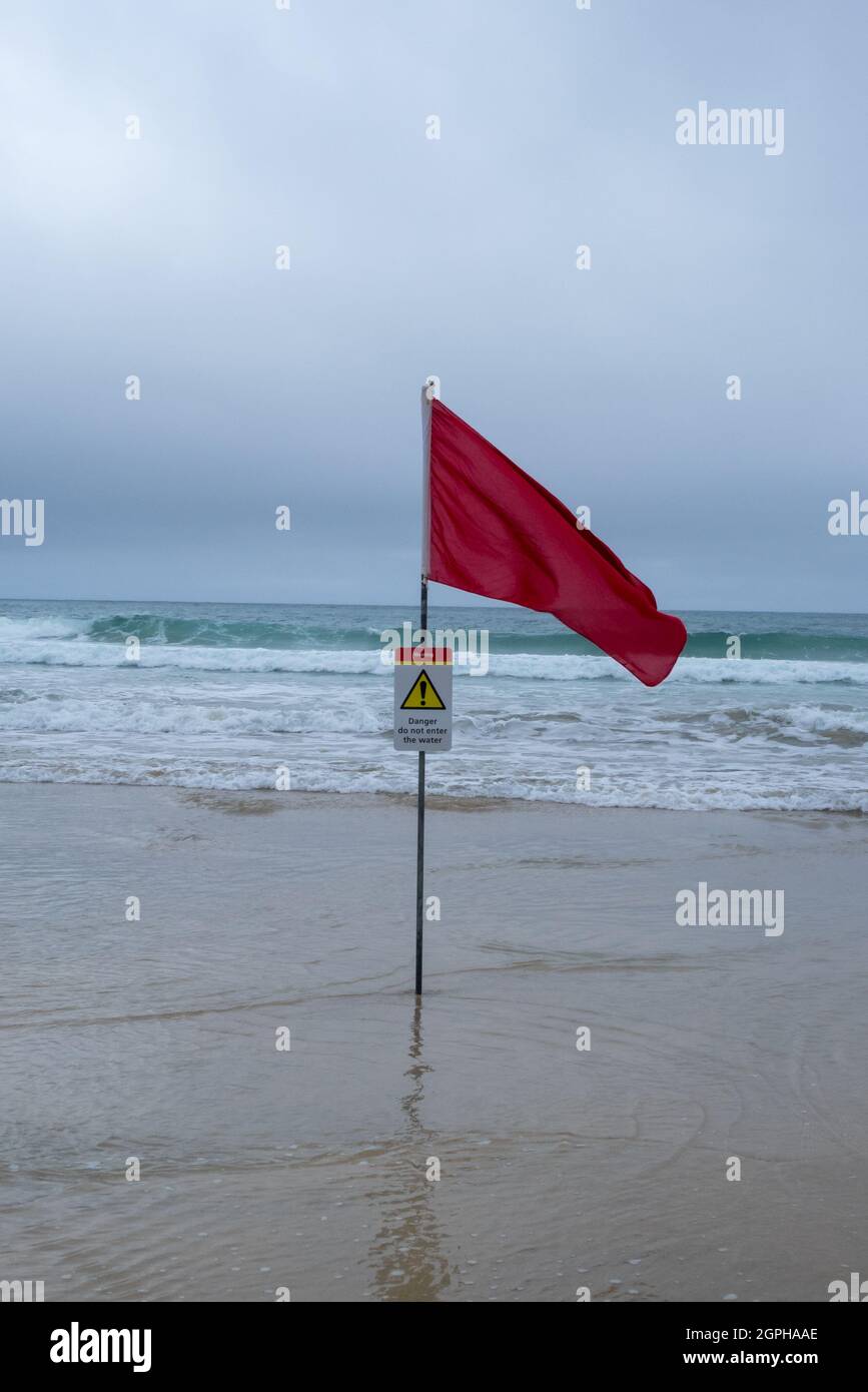 A Red Lifeguards Warning Flag (With Warning Sign) On A Cornish Beach Stock Photo