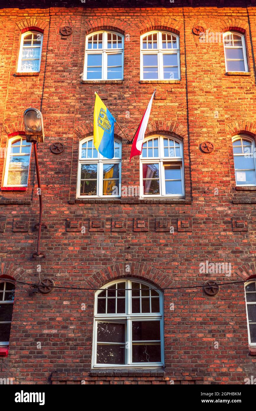 Facade of an old, traditional, silesian brick block house in Nikiszowiec, Katowice, Poland. Polish and Silesian flag hanging outside the building. Stock Photo