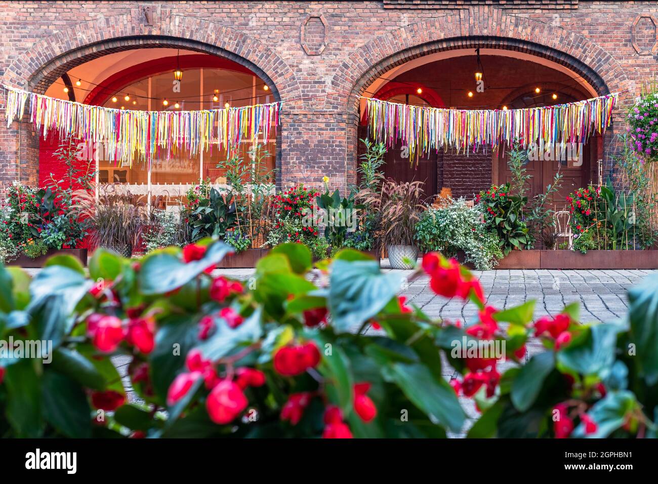 Detail of the arcade in an old, traditional, silesian brick block house in Nikiszowiec, Katowice, Poland. Colorful ribbons hanging as a decoration in Stock Photo