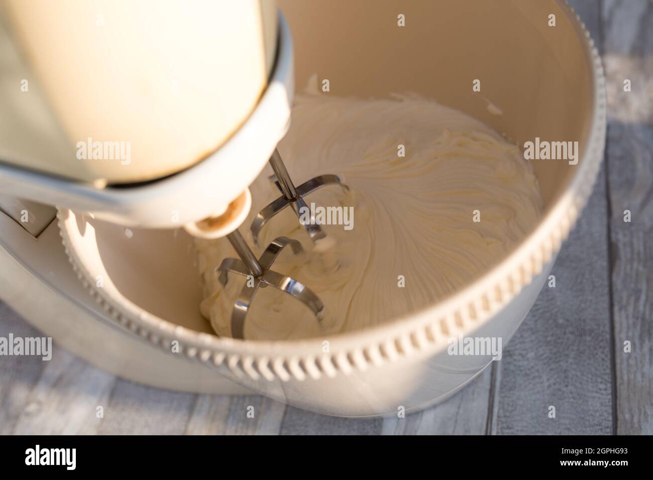 Step by step the process of making sour cream. Sour cream is whipped in a mixer container with whisk. Stock Photo