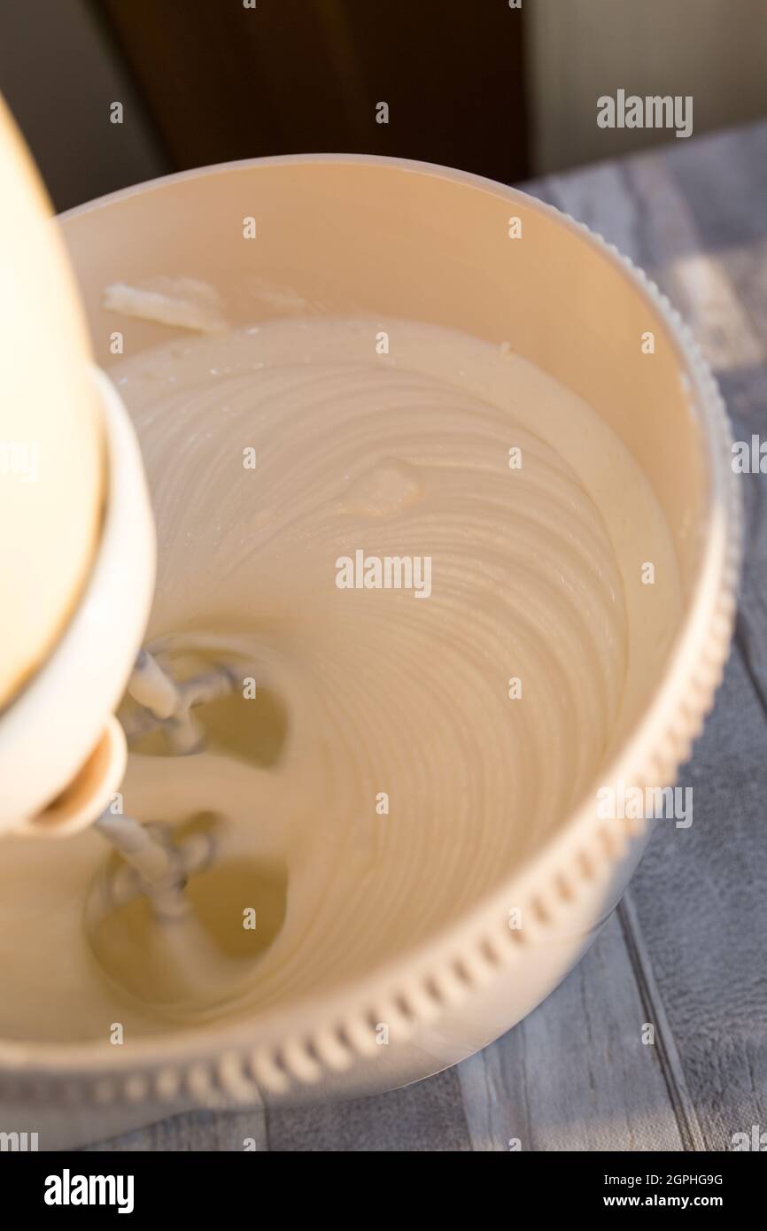 Step by step the process of making sour cream. Sour cream and sugar are whipped in a mixer bowl with whisk. Stock Photo
