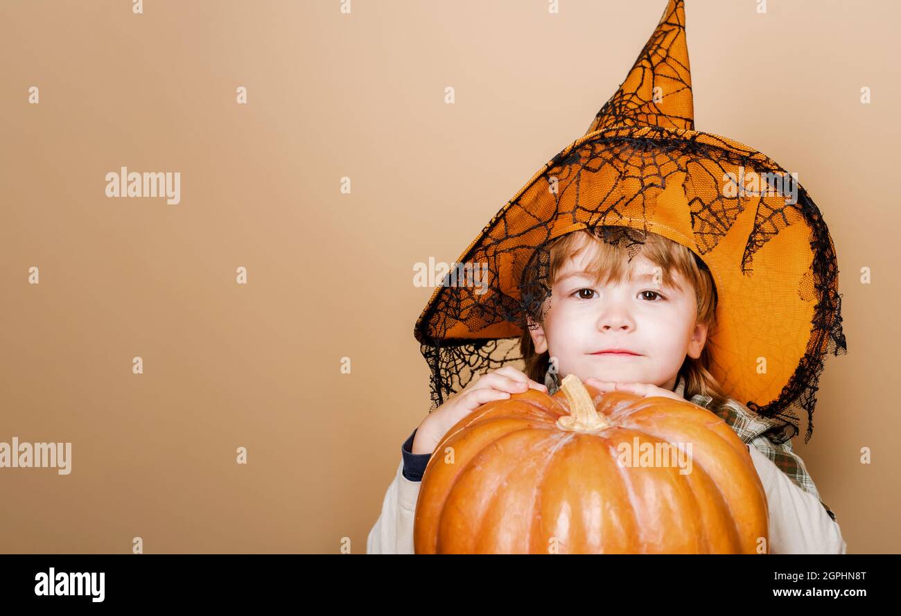 Happy Halloween. Cute boy in witch hat with big pumpkin. Jack-o-lantern. Trick or treat. Copy space. 31 october. Stock Photo
