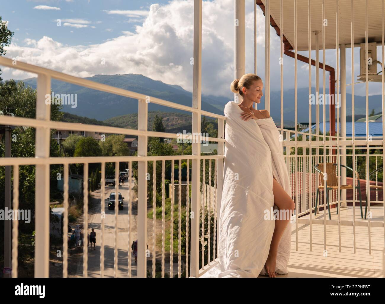 The girl sits on the balcony of the mountains and the blue sky on the background of beauty balcony caucasian lifestyle, young outdoor relax outside re Stock Photo