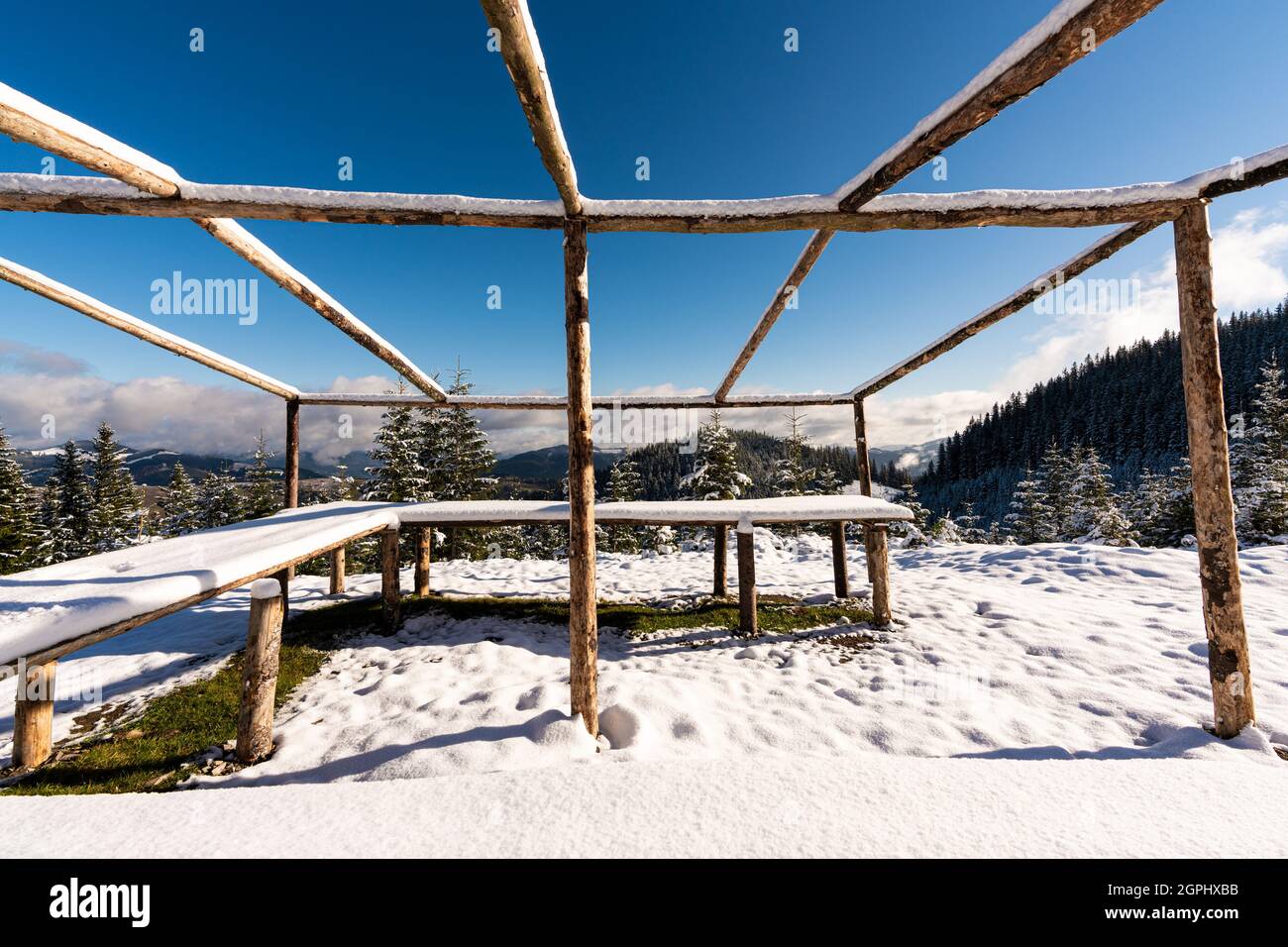 A large, uncovered gazebo on the top of the mountain stands on a snow ...