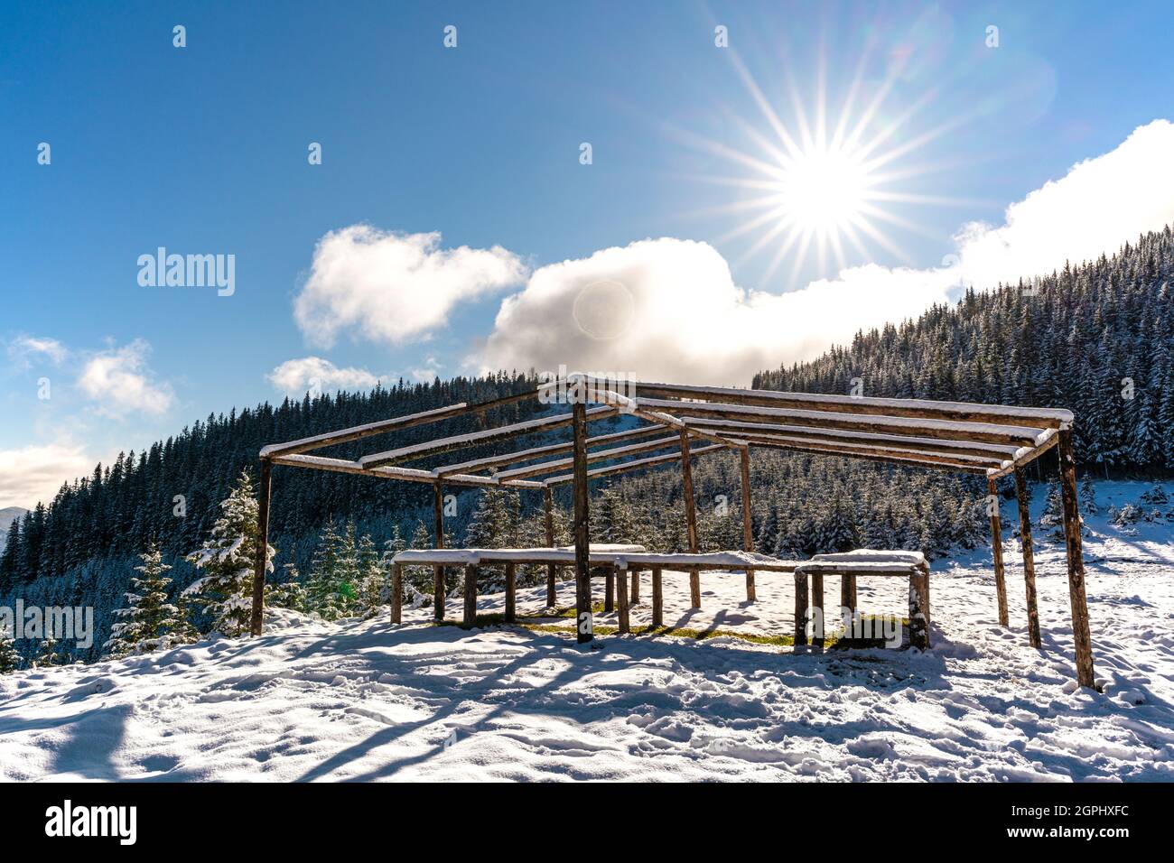 A large, uncovered gazebo on the top of the mountain stands on a snow ...