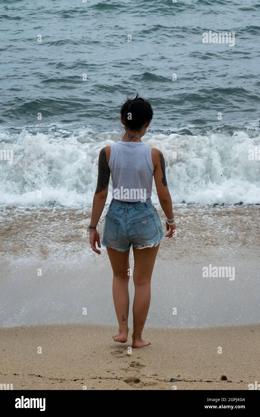 Santa Marta, Magdalena, Colombia - May 22 2021: Young Woman is Wetting her Feet on the Seashore at the Beach Stock Photo