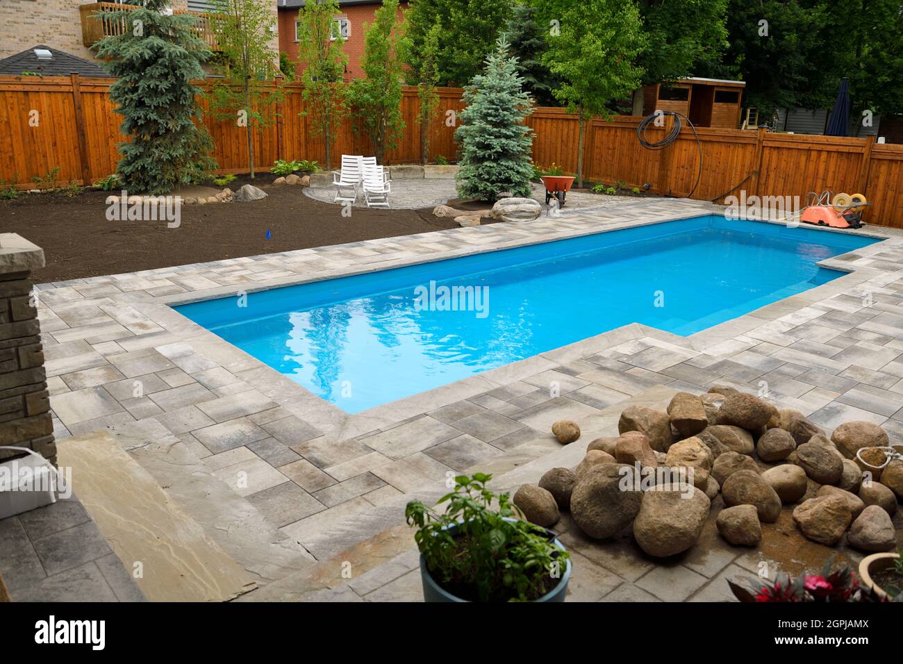 Newly installed swimming pool in Spring with unfinished, back yard landscaping construction ongoing Stock Photo