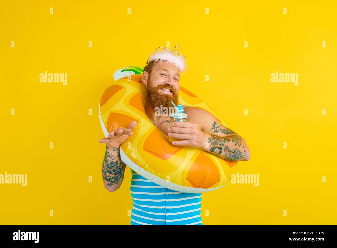 man with life buoy and princess crown drinks a fruit juice Stock Photo