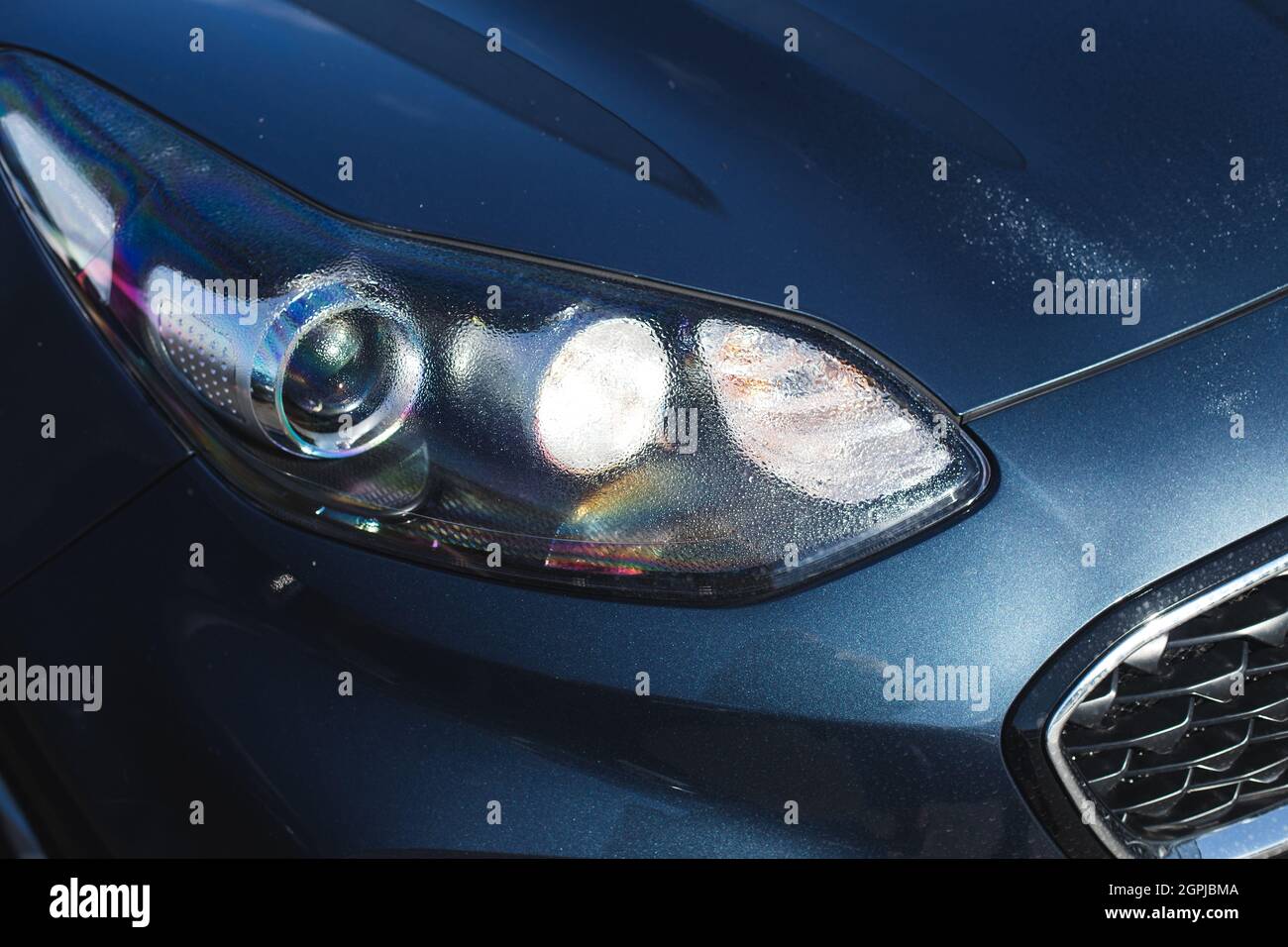 Hood of modern car after rain with drops on a headlight and body. Stock Photo