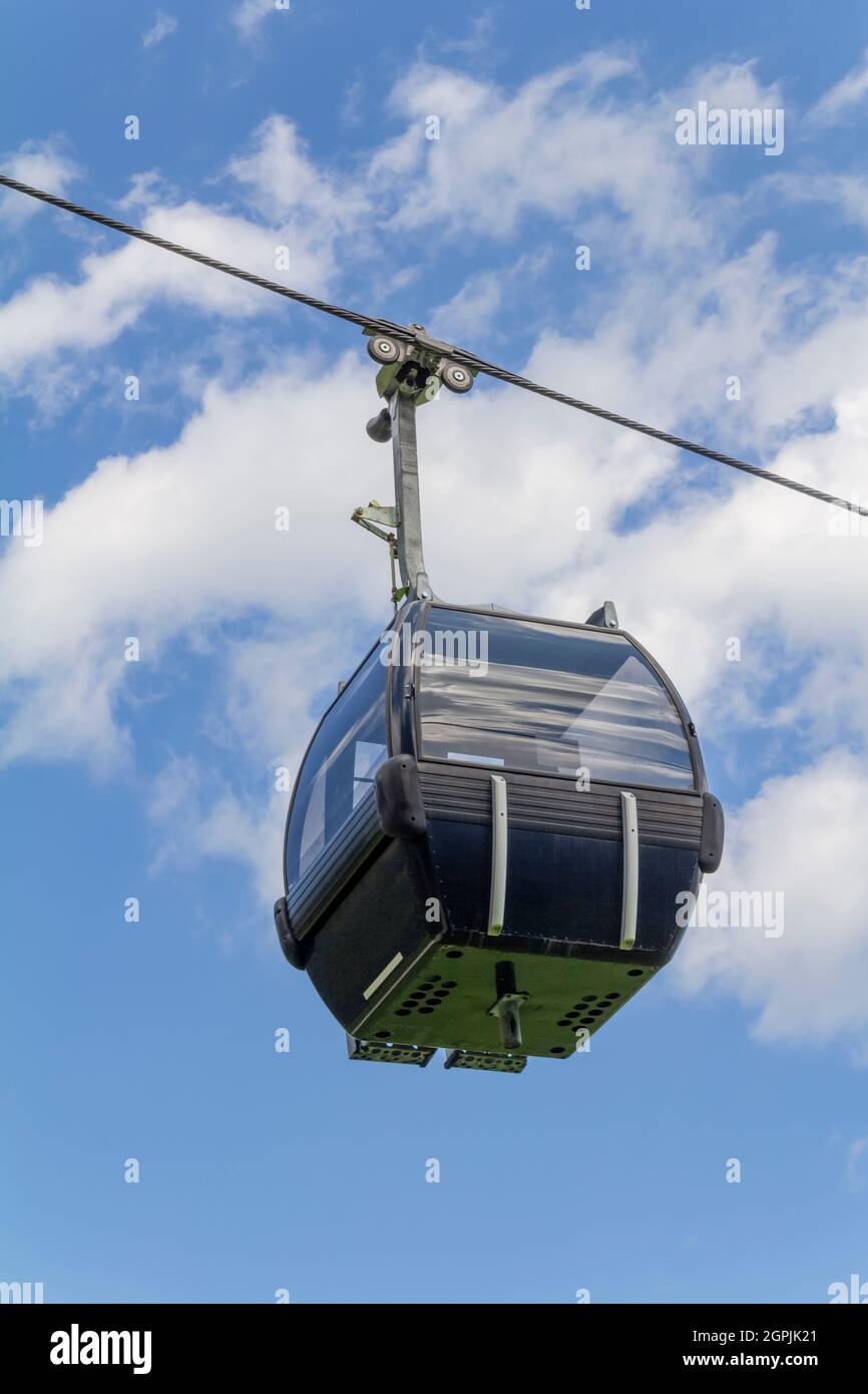 Low angle view of a lift gondola in front of blue sky and some clouds Stock Photo