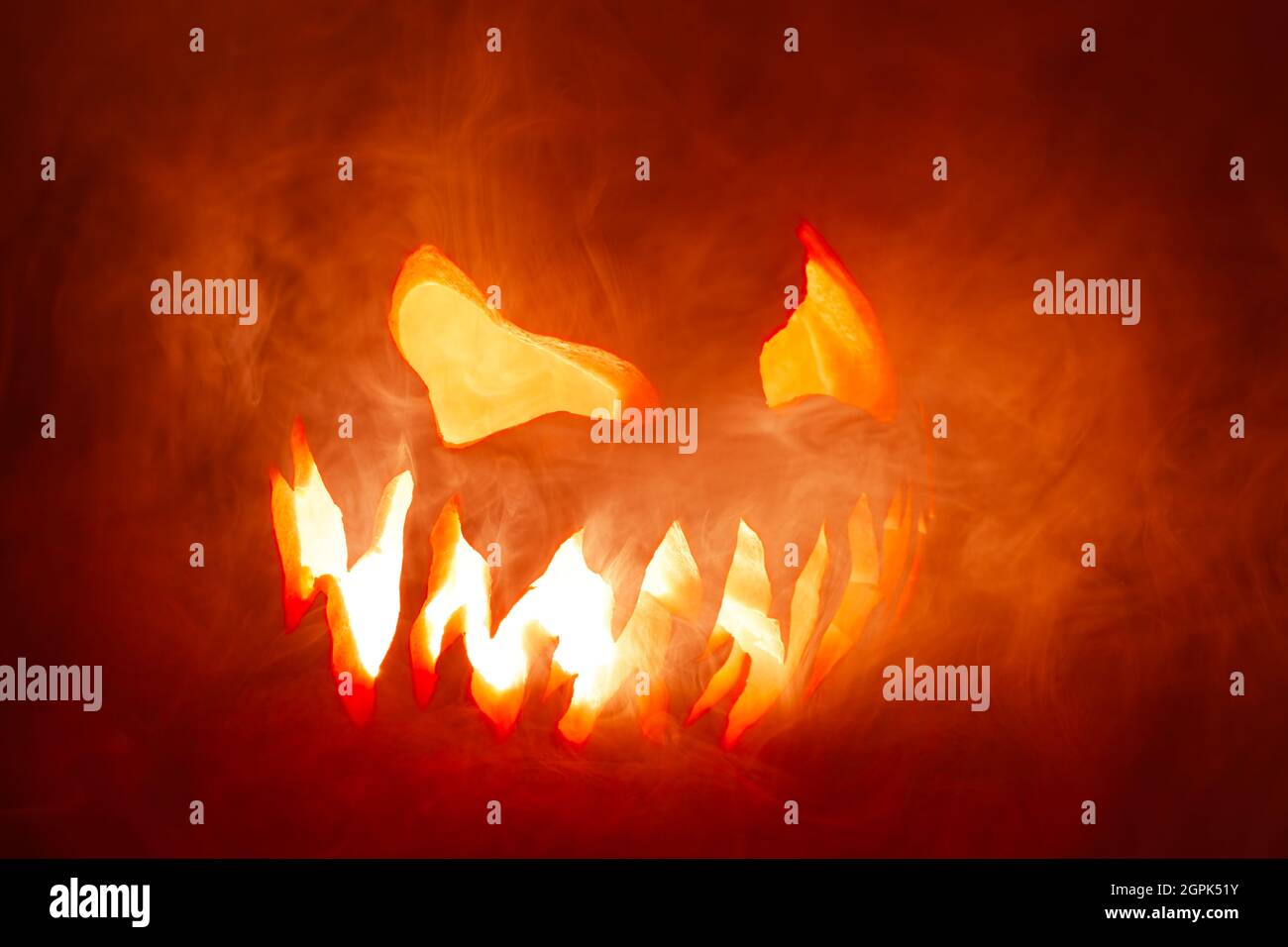 Scary Halloween jack o lantern face glowing in smoke and fire Stock ...