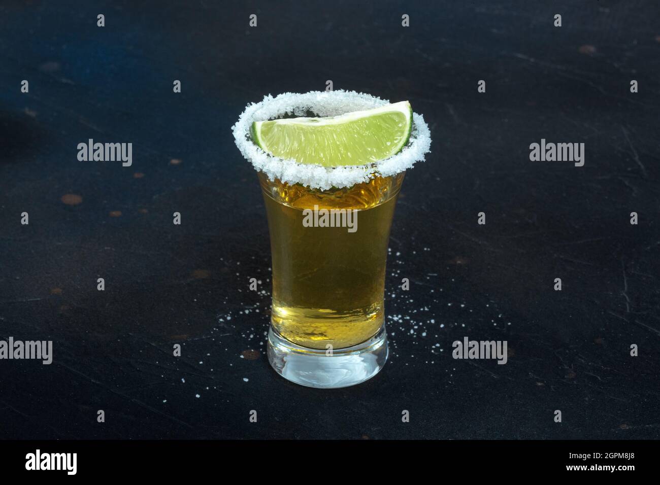 Gold tequila shot, with a salt rim and a lime slice, an angle close-up ...