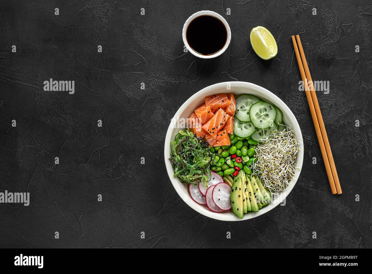 Keto diet poke bowl with salmon, avocado, and edamame beans. over dark background. Stock Photo