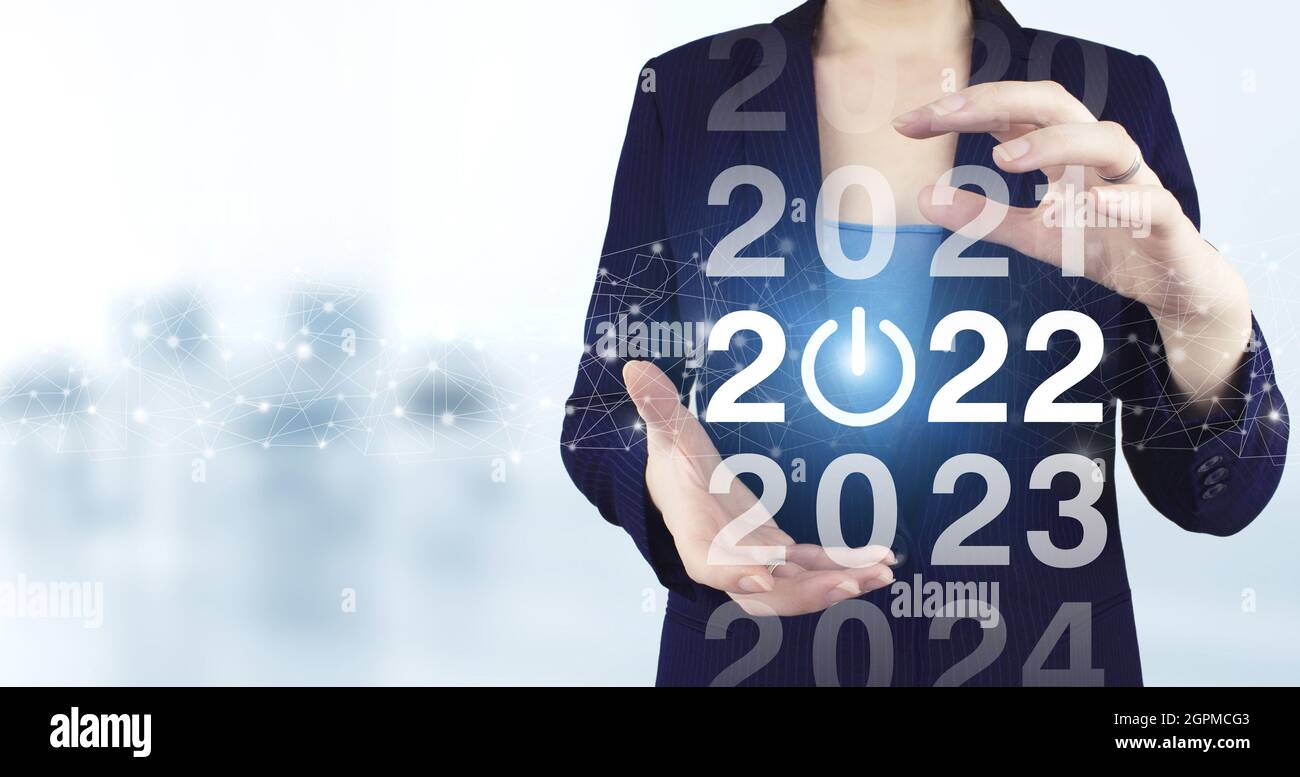 Loading year 2021 to 2022. Start concept. Two hand holding virtual holographic 2022 icon with light blurred background. Welcome year 2022. Business ne Stock Photo