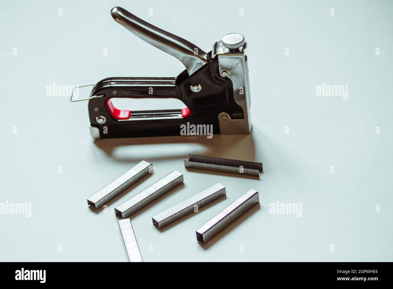 Furniture construction stapler next to staples on a white background.  Stock Photo