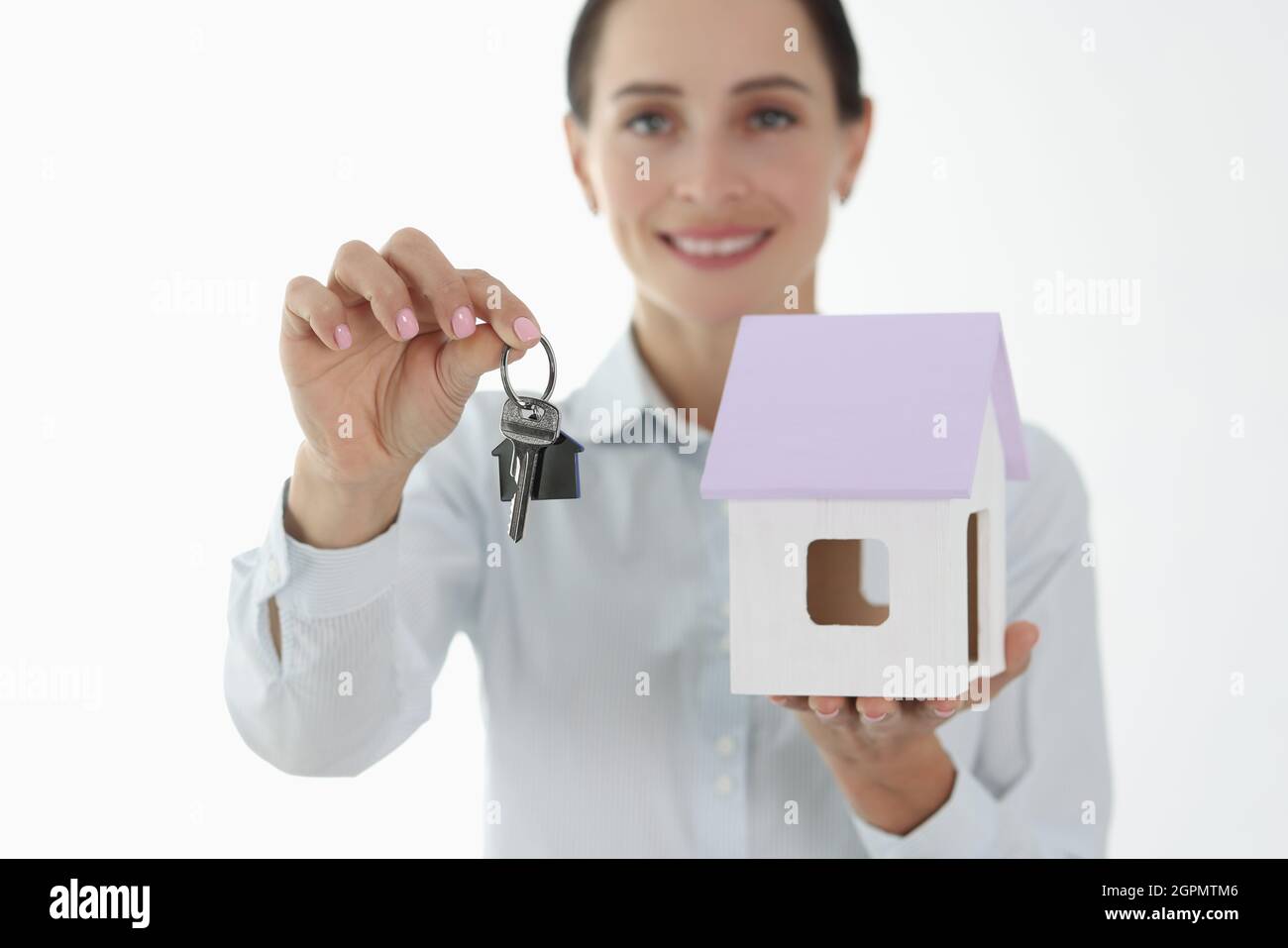Smiling female agent holding small house and keys Stock Photo - Alamy