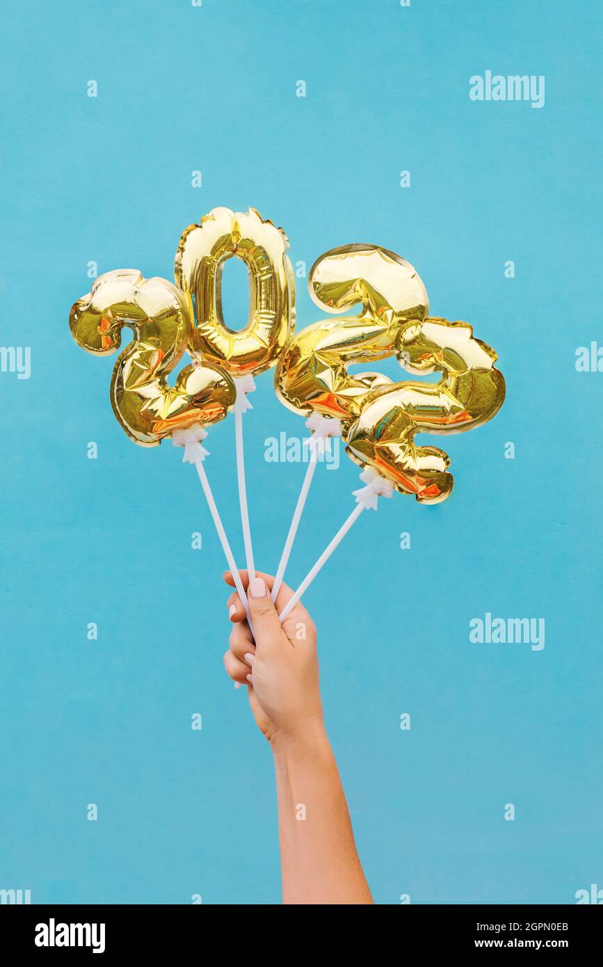 New year number 2022 made of golden balloons on a stick in female hands New year number 2022 from golden balloons on a stick in female hands. Concept Stock Photo