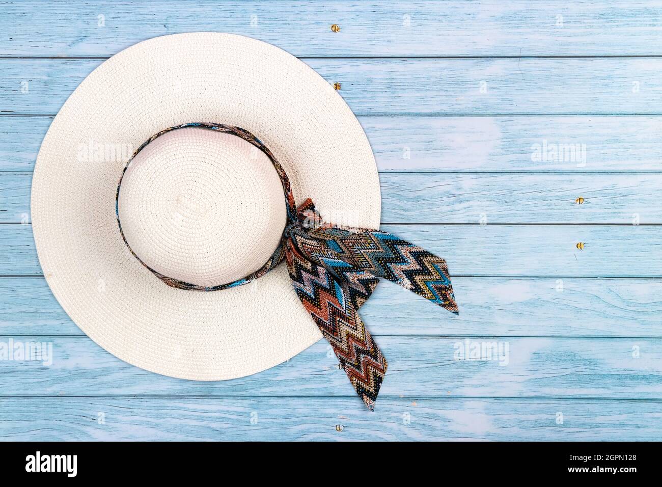 Top view of a straw white hat lying on a blue wooden background.The ...