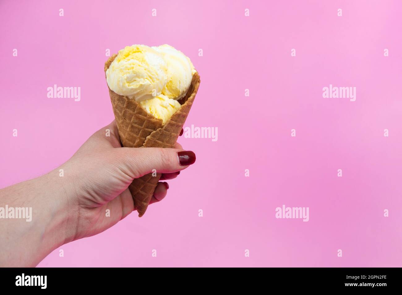 A hand holds an ice cream cone on a pink popsicle background in a ...