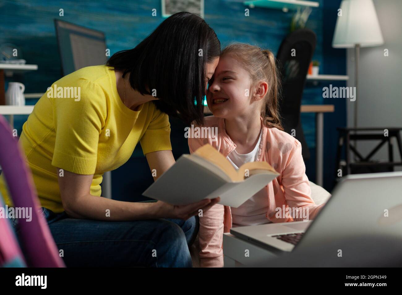 Parent helping little child with school homework sitting beside reading ...