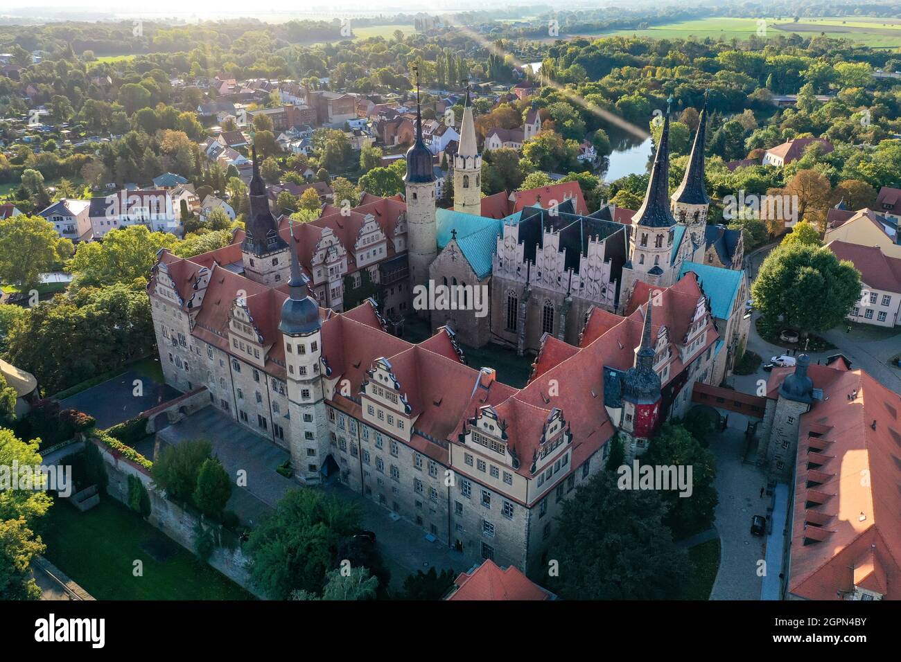 Merseburg, Germany. 30th Sep, 2021. The morning sun shines on Merseburg Cathedral. (Aerial photo with drone) A three-day festival in Merseburg from 1 to 3 October will commemorate the consecration of the cathedral 1000 years ago. Among the highlights of the program under the motto 'Consecrated for Eternity' is a procession during which the cathedral will ceremoniously receive a new bell. According to tradition, Merseburg Cathedral was consecrated on 1 October 1021 in the presence of Emperor Heinrich II and his wife Kunigunde. Credit: Jan Woitas/dpa-Zentralbild/dpa/Alamy Live News Stock Photo