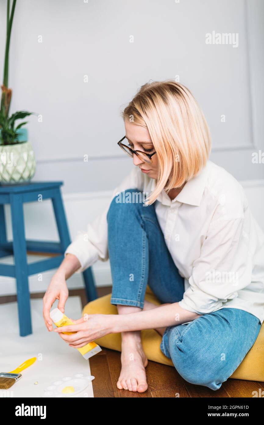 Young woman artist is painting at home in a creative studio setting.  Stock Photo