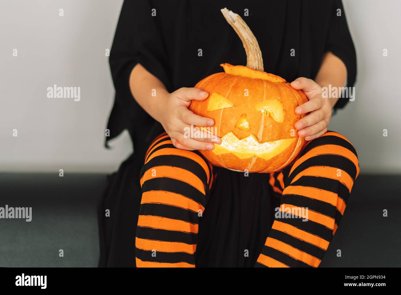 Child in witch costume holding jack-o-lantern pumpkin Stock Photo