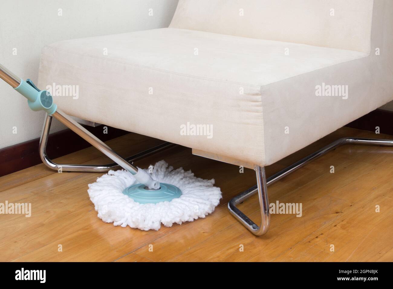 Housekeeper wiping wooden floor with mop under sofa Stock Photo Alamy