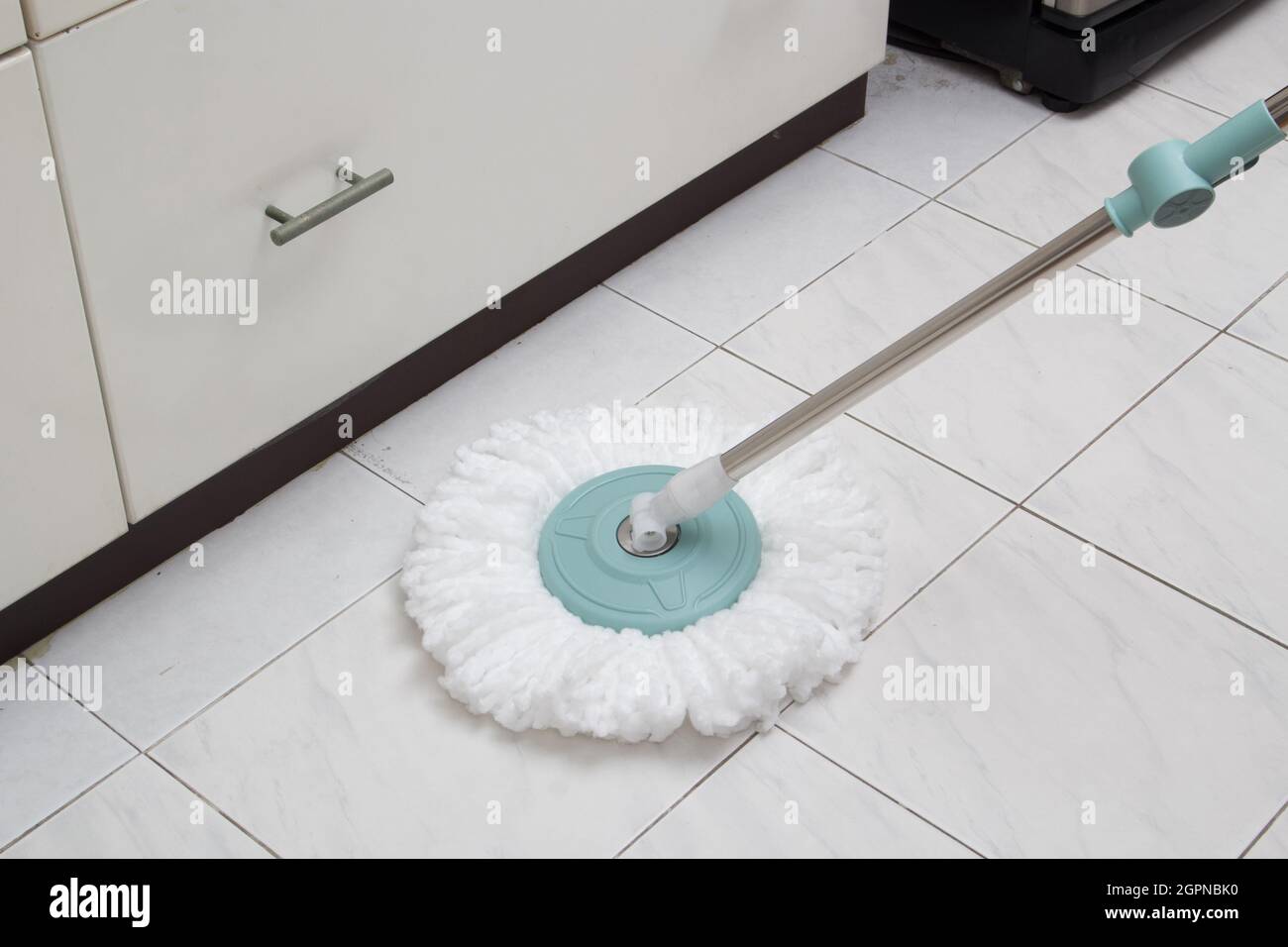 Blue cleaning mop on white ceramic tile floor in the kitchen Stock ...