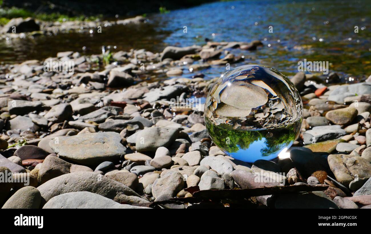 Lensball photography with a crystal ball in the sunlight on a stone bank of a river Stock Photo