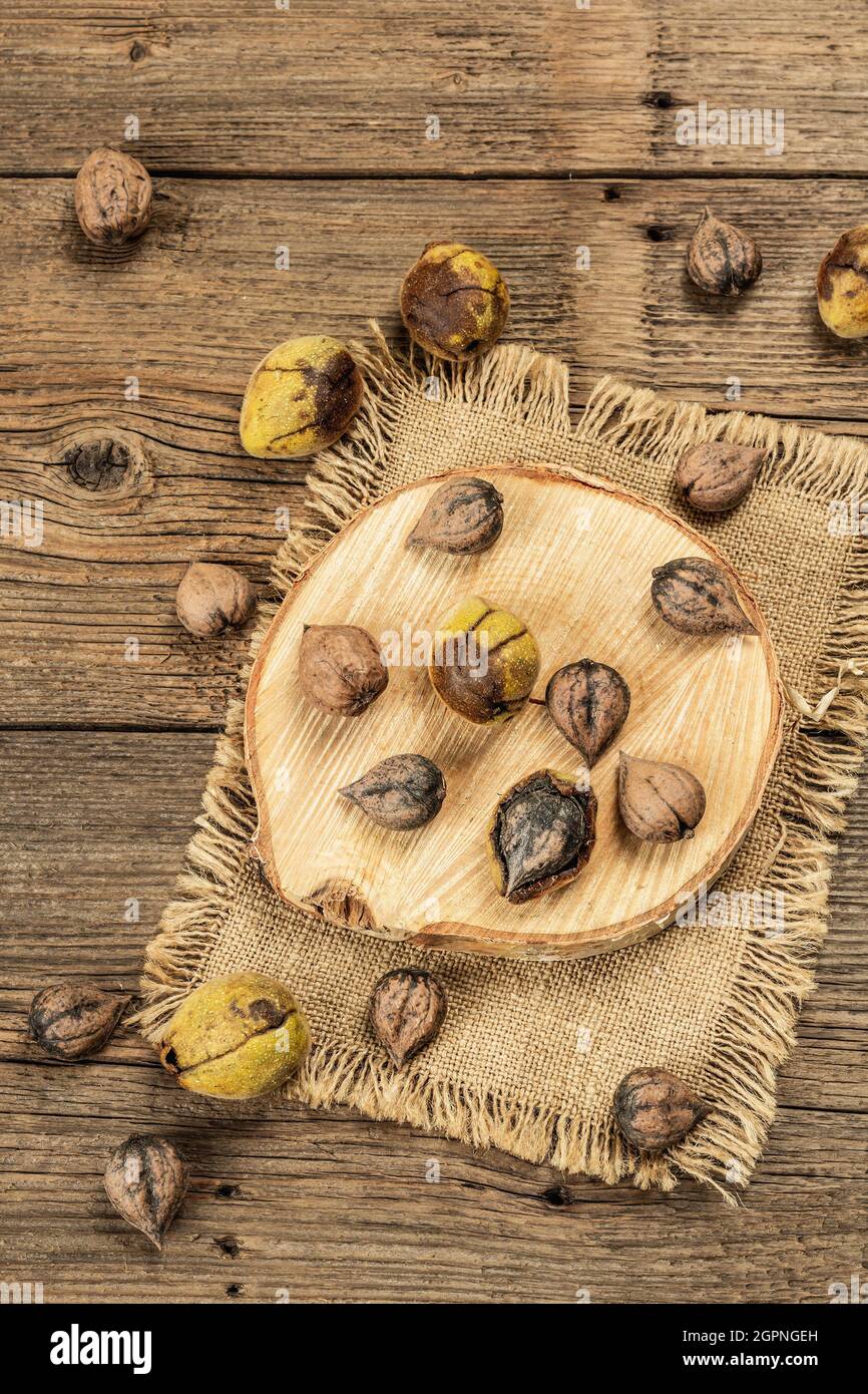 Ripe Juglans cordiformis Maxim or heart-shaped walnut. Young green and unpeeled whole nuts on a stand. Vintage wooden boards, top view background Stock Photo