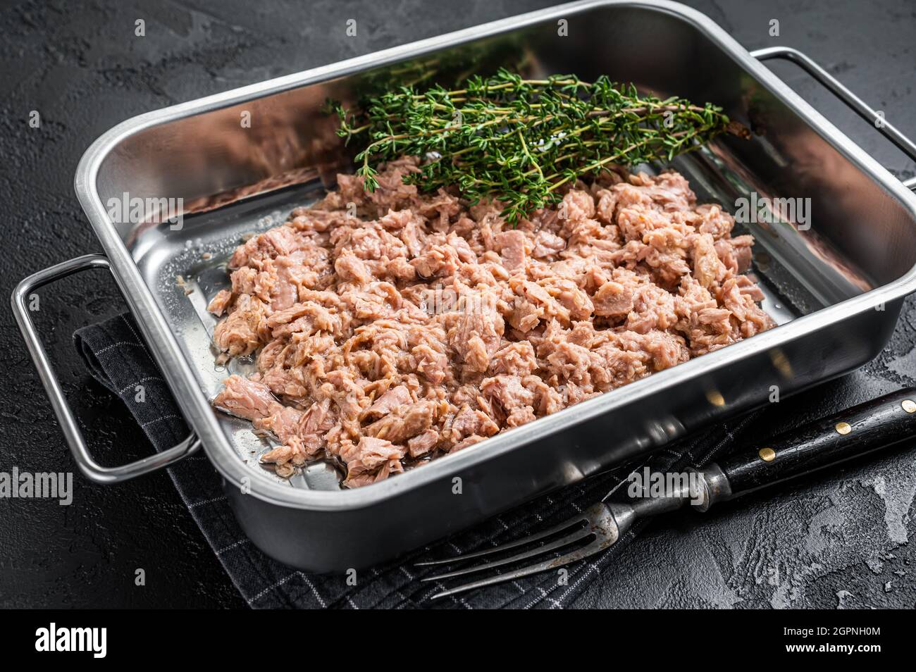 Tuna canned fish with olive oil in a tray . Black background. top view