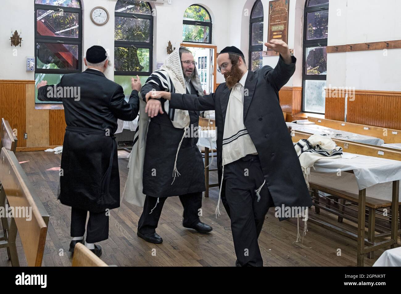 Orthodox Jewish men dance to celebrate the joyous holiday of Sukkos. In a synagogue in Williamsburg, Brooklyn, New York City. Stock Photo