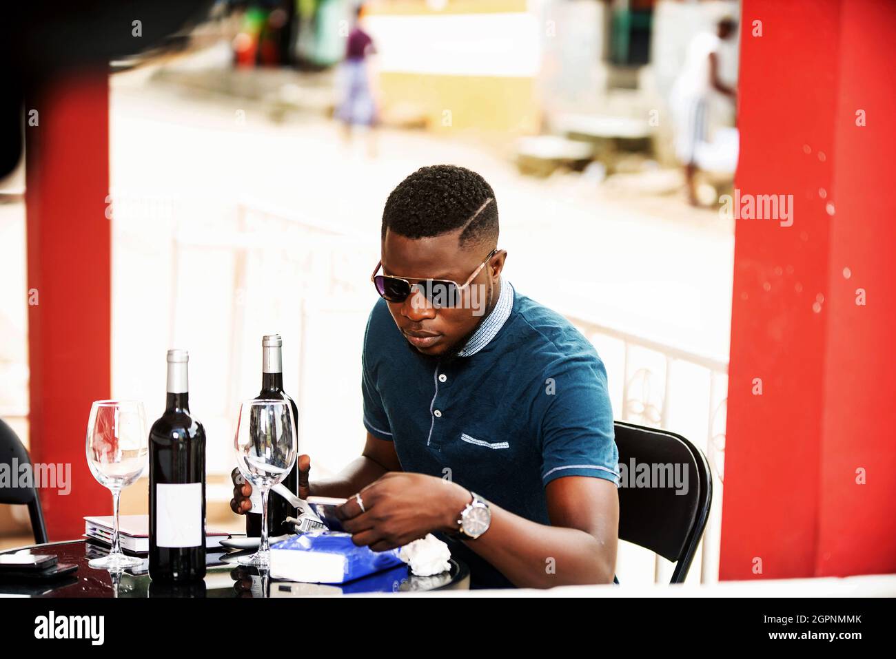 handsome young man wearing sunglasses sitting with bottles of red