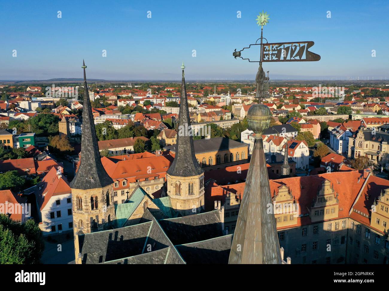 30 September 2021, Saxony-Anhalt, Merseburg: A weather vane with the year 1727 rotates on a tower at Merseburg Cathedral. A three-day festival in Merseburg from 1 to 3 October commemorates the consecration of the cathedral 1000 years ago. One of the highlights of the program under the motto 'Consecrated for Eternity' is a procession during which the cathedral will ceremoniously receive a new bell. According to tradition, Merseburg Cathedral was consecrated on October 1, 1021 in the presence of Emperor Heinrich II and his wife Kunigunde. (Aerial view with drone) Photo: Jan Woitas/dpa-Zentralbil Stock Photo