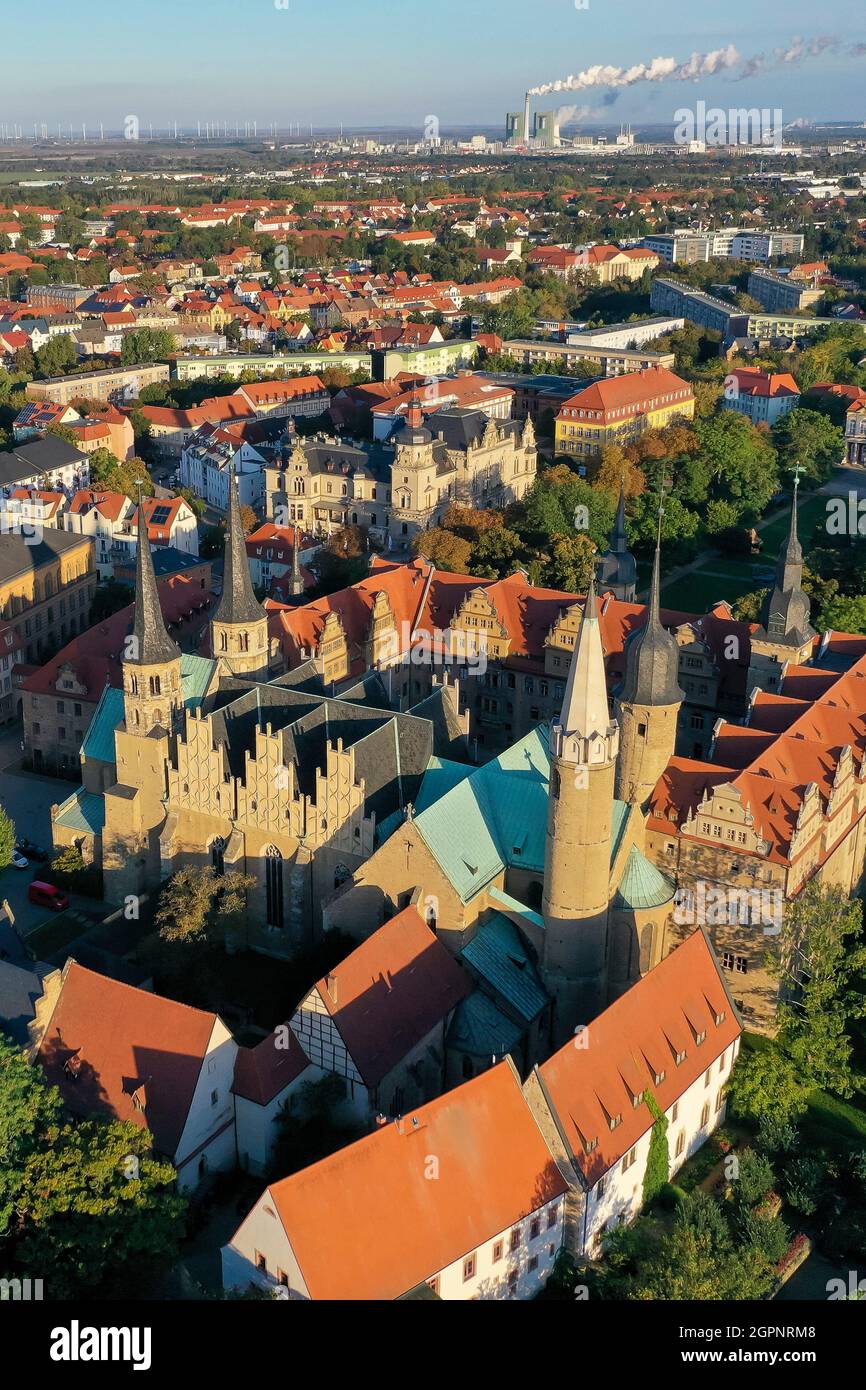 Merseburg, Germany. 30th Sep, 2021. The morning sun shines down on Merseburg Cathedral. A three-day festival in Merseburg from 1 to 3 October commemorates the consecration of the cathedral 1000 years ago. One of the highlights of the program under the motto 'Consecrated for Eternity' is a procession during which the cathedral will ceremoniously receive a new bell. According to tradition, Merseburg Cathedral was consecrated on October 1, 1021 in the presence of Emperor Heinrich II and his wife Kunigunde. (Aerial view with drone) Credit: Jan Woitas/dpa-Zentralbild/dpa/Alamy Live News Stock Photo